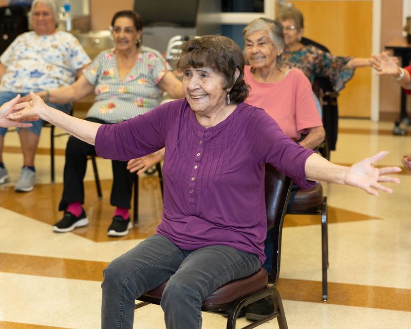 A participant opens her arms wide in a seated stretch.